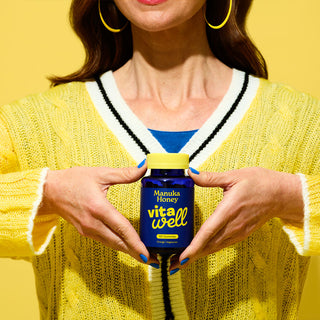 Women in yellow jumper holding Manuka Honey Supplement bottle