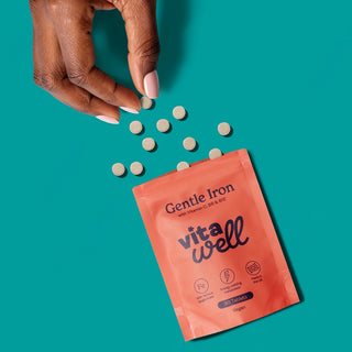 Hand pouring Gentle Iron tablets from a vita well package 