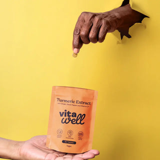 Person holding a Vitawell turmeric extract package against a yellow background