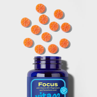 Vitamin supplement bottle labeled 'Focus' with orange gummies on a light grey background