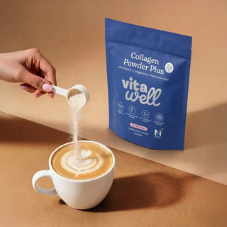 Vitawell collagen powder being added to a cup of coffee with a blue package in the background.