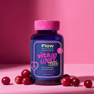 Vitawell Teen supplement bottle with cranberries on a pink background