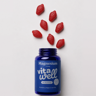 Blue bottle of Vitawell magnesium gummies with strawberry-shaped capsules on a light grey background